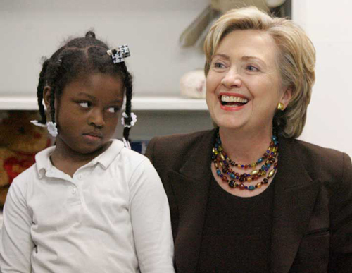 A young Black girl looks skeptically at Hillary Clinton